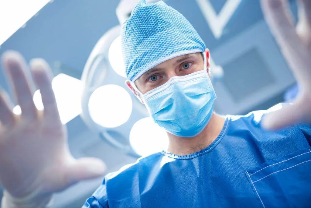 Portrait einer Operationstechnischen Assistenz beim anziehen der der sterilen Handschuhe