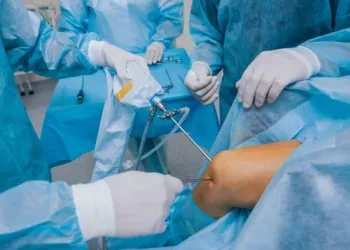 Knie-Arthroskopie Chirurgie. Orthopäden in Teamarbeit im Operationssaal mit modernen arthroskopischen Instrumenten. Knieoperation. Krankenhaushintergrund